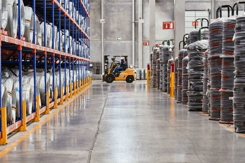 Forklift driving down a warehouse aisle, the kind of site where phone systems for logistics keep depot teams connected