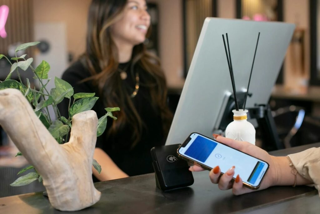 Smiling front desk receptionist serving a guest who is paying by phone at the counter