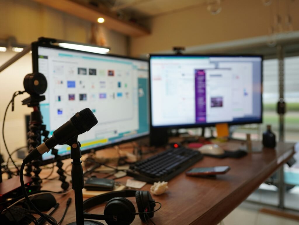 Editing desk with two monitors, a microphone and headphones in a studio that uses phone systems for media