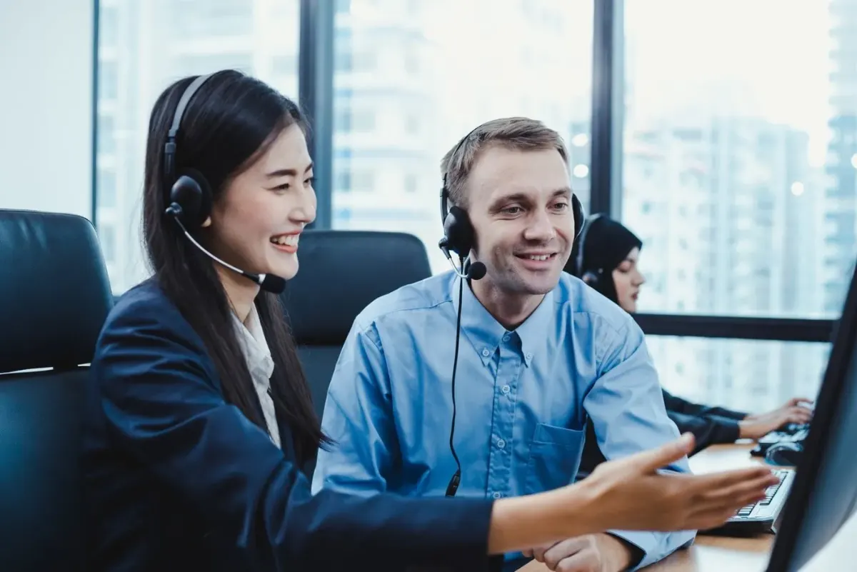 AI-Powered Contact Centre Agent and team leader on headsets reviewing a call in an AI contact centre